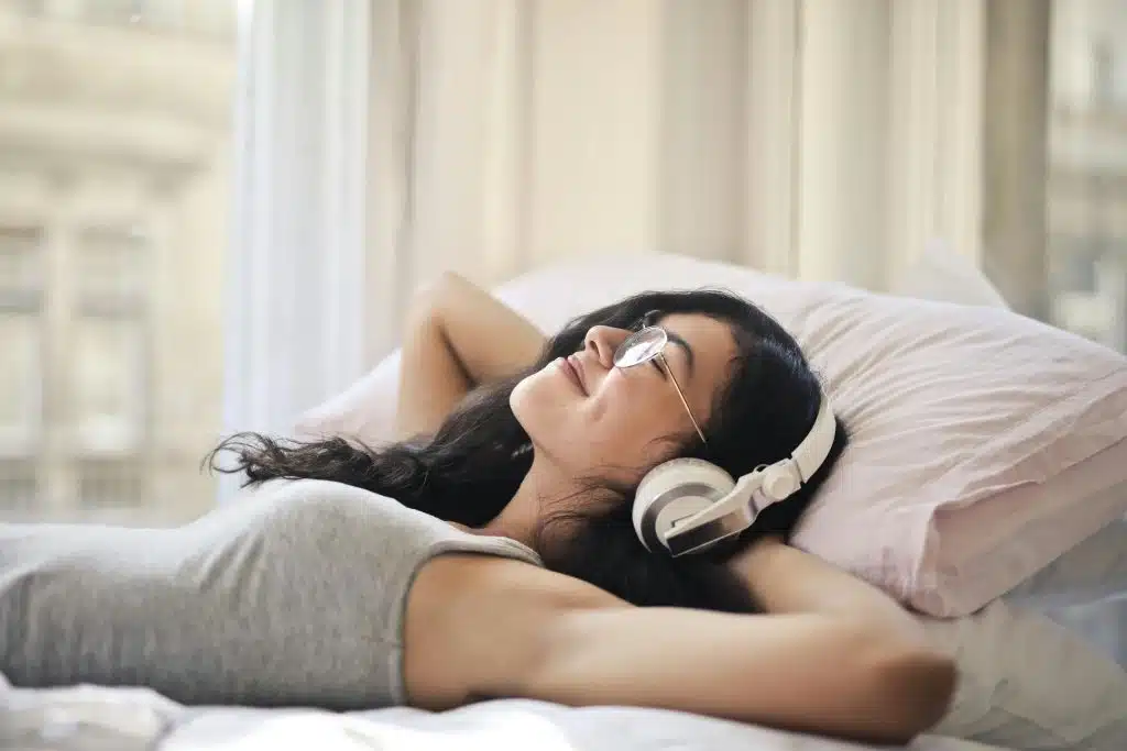 Frau auf ihrem Bett, die Musik auf Spotify hört.